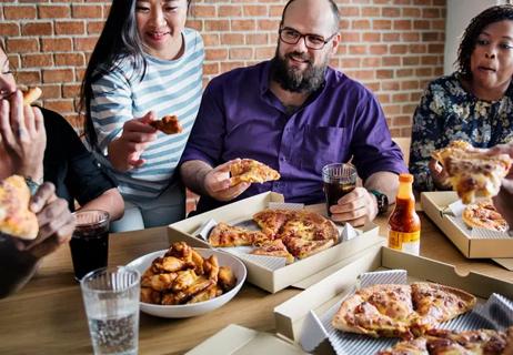 group of people eating pizza and wings