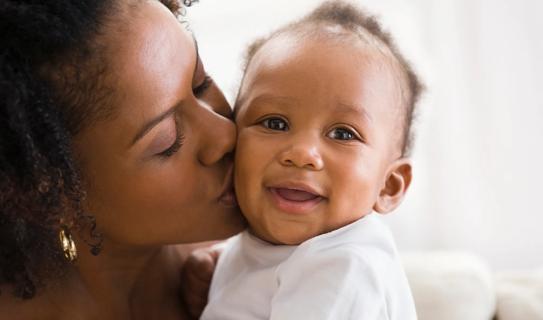 Caregiver kissing smiling baby