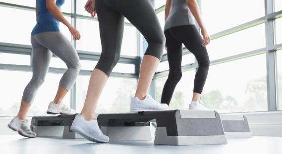 Group of people exercising, doing step-ups on exercise steps