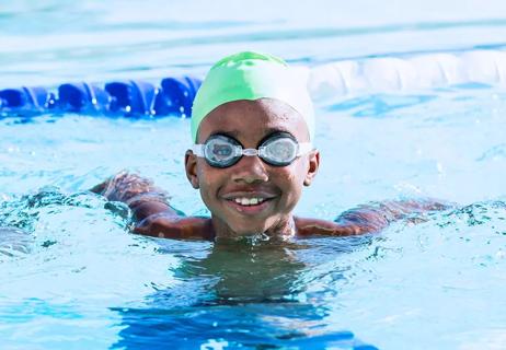 boy swimming in pool with goggles