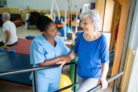 Physical therapist helping person with walking in therapy gym