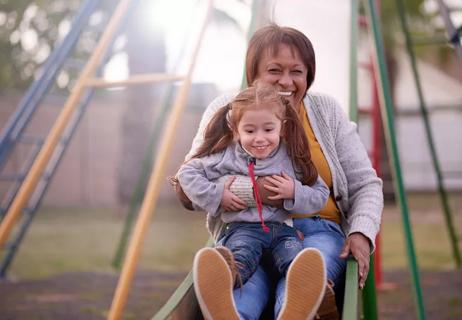 Babysitter and child braving the playground slide