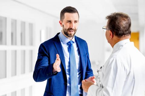 Man in blue suit talking to man in white coat