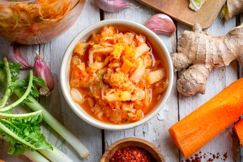 Bowl of kimchi with ingredients surrounding it on the table