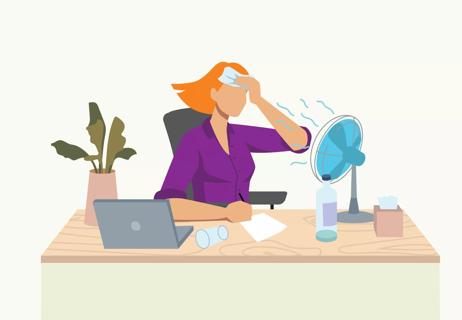 person at desk sweating and using a desk fan