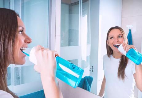 Person using water dental flosser in bathroom.