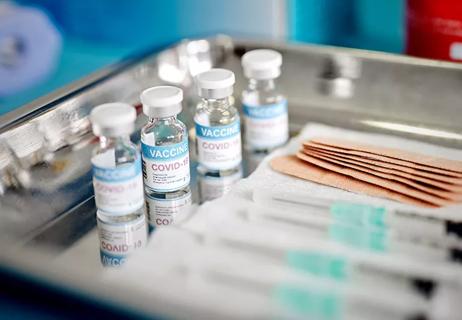A metal tray with vials of the COVID-19 vaccine, bandages and needles