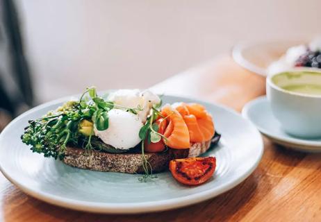 A pescatrian breakfast of eggs, salmon, tomato and avocado on wheat toast.