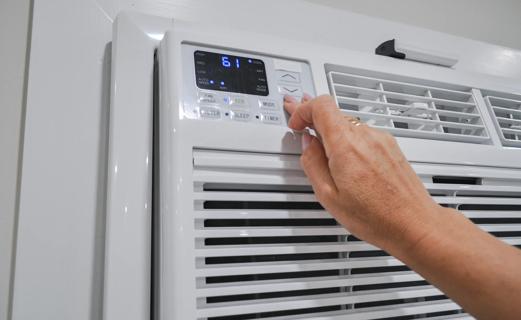 Hand adjusting the temperature on AC unit