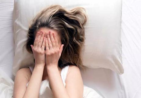 person covering face in bed in embarrassment