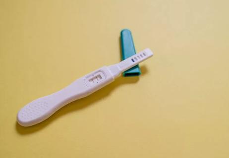 Ovulation strip with two lines visible and cap off against a yellow background