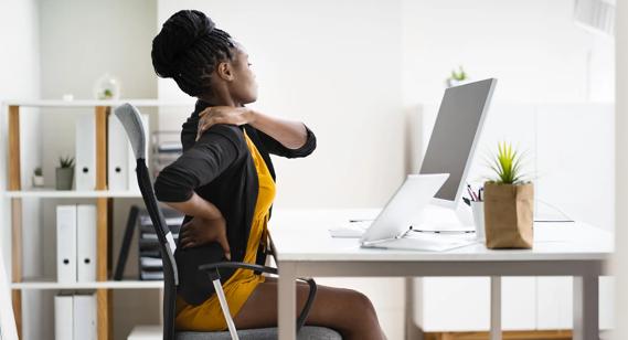 Person stretching their aching shoulder blade and back while sitting in an office chair at a desk
