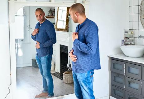 man checking his weight by looking in the mirror BMI