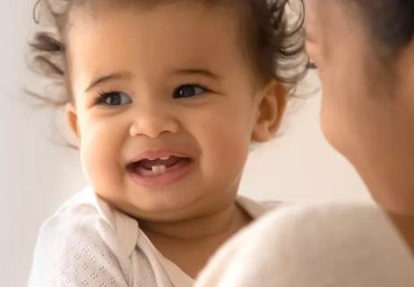 Smiling baby showing off her first teeth.