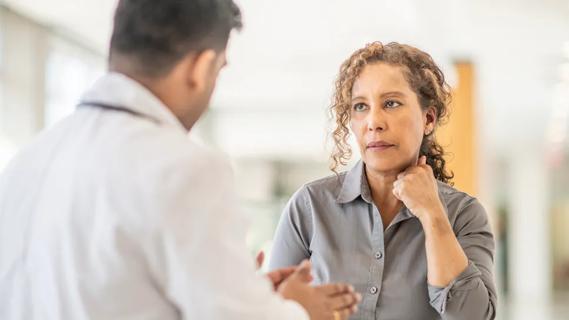 woman looking concerned as she listens to a doctor speak to her