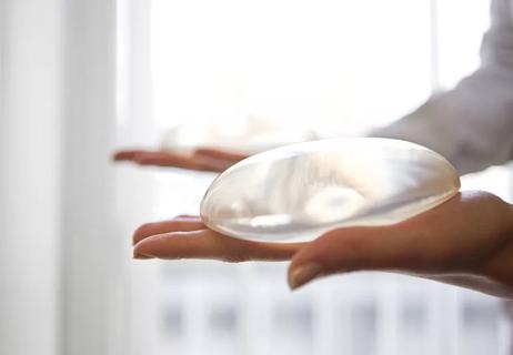 Two hands holding breast implants