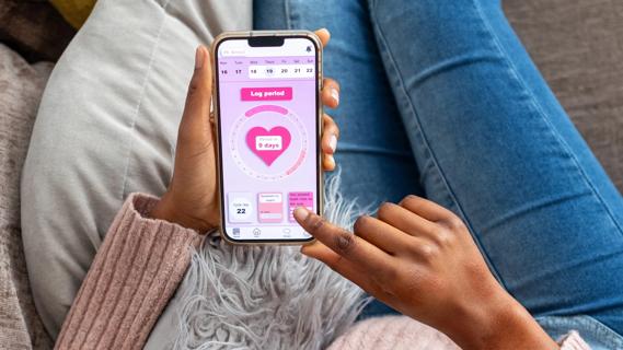 Hands holding smartphone, open to on a period-tracking app