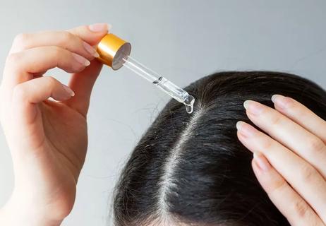 Person applying hair oil to scalp.