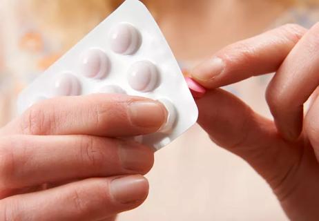 Close up of ibuprofen being punched from a blister pill pack.