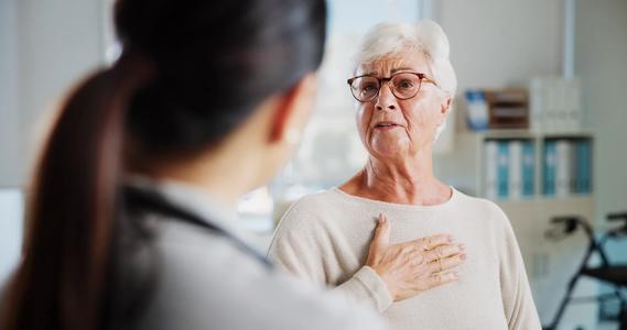 Older woman with hand on their chest talking with healthcare provider in office