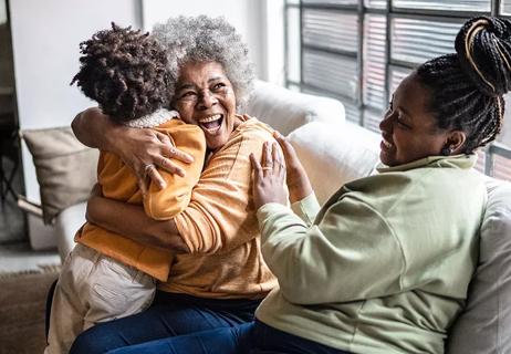 Grandma enthusiastically embraces grandson while happy daughter looks on.