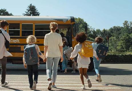 group of children and parent walking to school bus