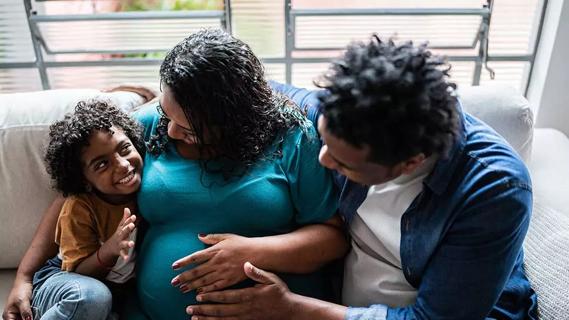 pregnant mother with father on couch with son