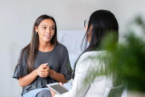 Teenager is seated and talking with provider