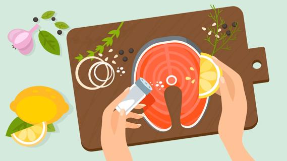 Hands prepping salmon with lemon and spices