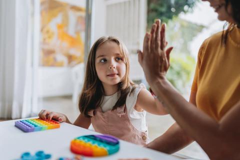 Child high-fiving parent as they play a game at a table