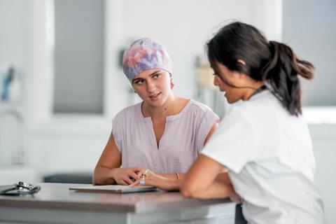 Female patient wearing scarf on head, talking with healthcare provider in office