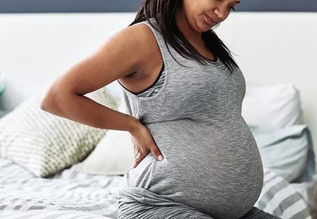 Pregnant woman with back pain getting out of bed