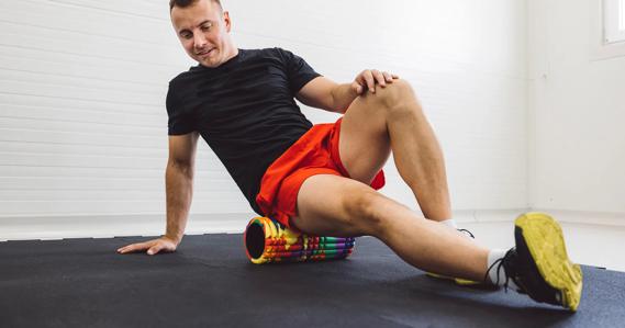 Person positioned on foam roller, stretching muscles