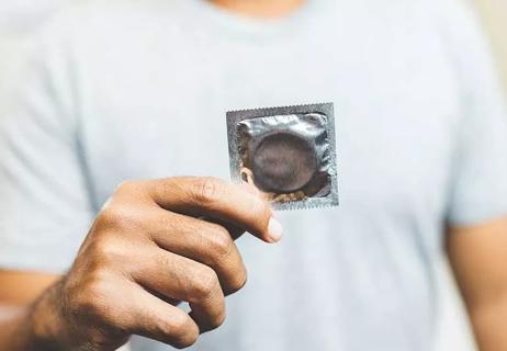 Man holding a wrapped condom.
