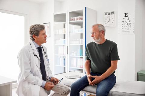 Healthcare provider talking to older patient sitting on exam table