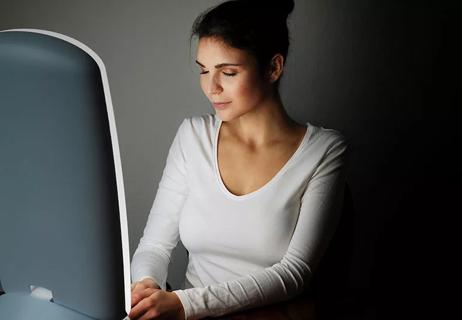 A person wearing a white long-sleeved shirt sitting with her eyes closed