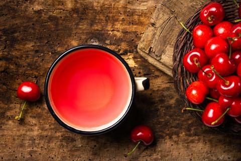 Mug of cherry juice, with fresh cherries in bowl