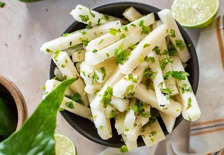 Sliced up pieces of jicama covered in cilantro and lime juice
