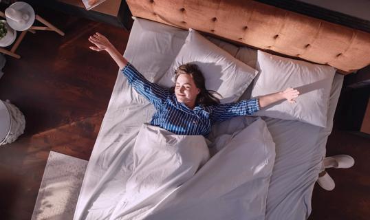 Happy person waking up in the morning, stretching in bed