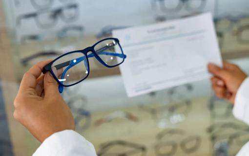 Eye doctor holding glasses and a prescription