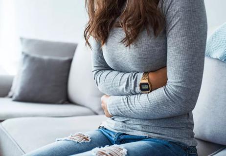 woman sitting on couch with severe stomach pain