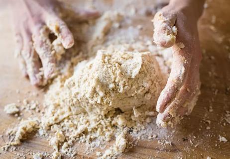 A person making a pie crust on a wood surface