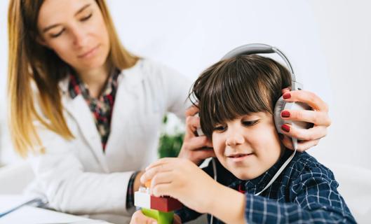Healthcare provider placing headphones on a young child