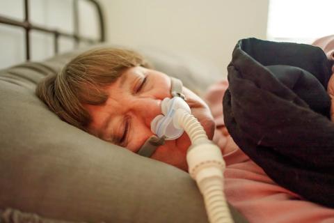 Older person sleeping with a continuous positive airway pressure machine, CPAP