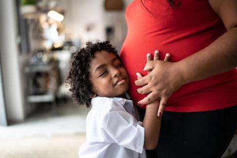 Child hugging mother who is pregnant