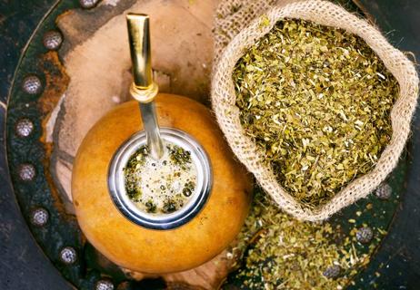 Top view of a bag of yerba mate tea and the traditional drinking gourd filled with the tea.