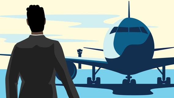 Person standing in airport looking out window at a plane