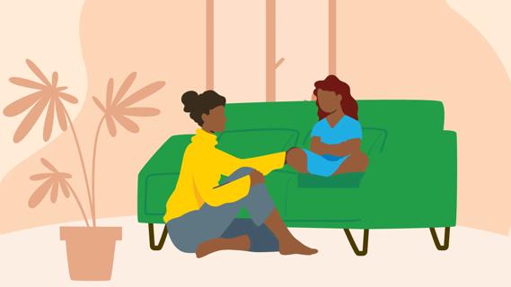 Caregiver sitting on floor next to couch with teen child sitting on it, talking