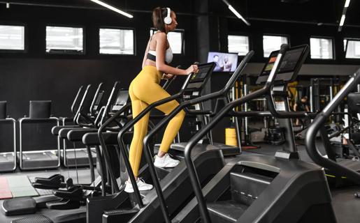 Person dressed in yellow yoda pants with headphones on using stair climber at gym