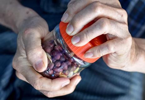 Elderly person trying to open a jar of peanuts.